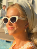 Kristen Wiig wears white cat-eye sunglasses in the series Palm Royale.